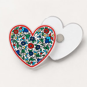 May include: Two heart-shaped magnets with a clear acrylic finish. One magnet displays a vibrant, intricate floral pattern featuring red, blue, yellow, and green flowers on a white background. The second magnet shows a plain white back with a circular metal magnet.