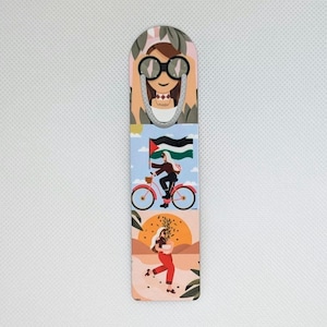 Könnte beinhalten: Rechteckiger Lesezeichen mit farbenfrohem Design. Es zeigt eine Frau mit Brille, eine Person, die mit einer Flagge Fahrrad fährt, und eine Person, die Pflanzen trägt. Das Lesezeichen hat eine silberne Metallschlaufe. Das Design ist bunt.