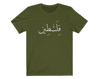 May include: Olive green t-shirt with white Arabic script across the chest. The short-sleeved shirt is made of a soft material and has a crew neck. The text is centered on the front of the shirt.
