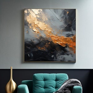 Puede incluir: Un sillón de color azul turquesa con una manta de color blanco y negro, un jarrón dorado y una mesa auxiliar dorada frente a una pared gris con una pintura abstracta enmarcada en oro y negro.