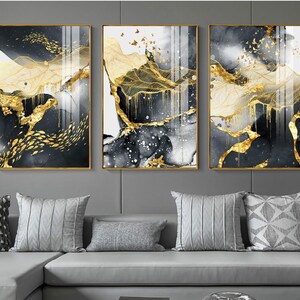 May include: Three abstract art prints with gold leaf accents on a black and white background. The prints are framed in gold and feature a landscape design with flowing lines and shapes.