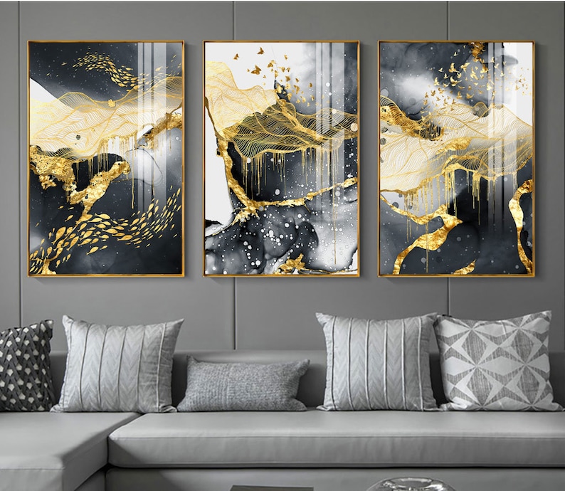 May include: Three abstract art prints with gold leaf accents on a black and white background. The prints are framed in gold and feature a landscape design with flowing lines and shapes.