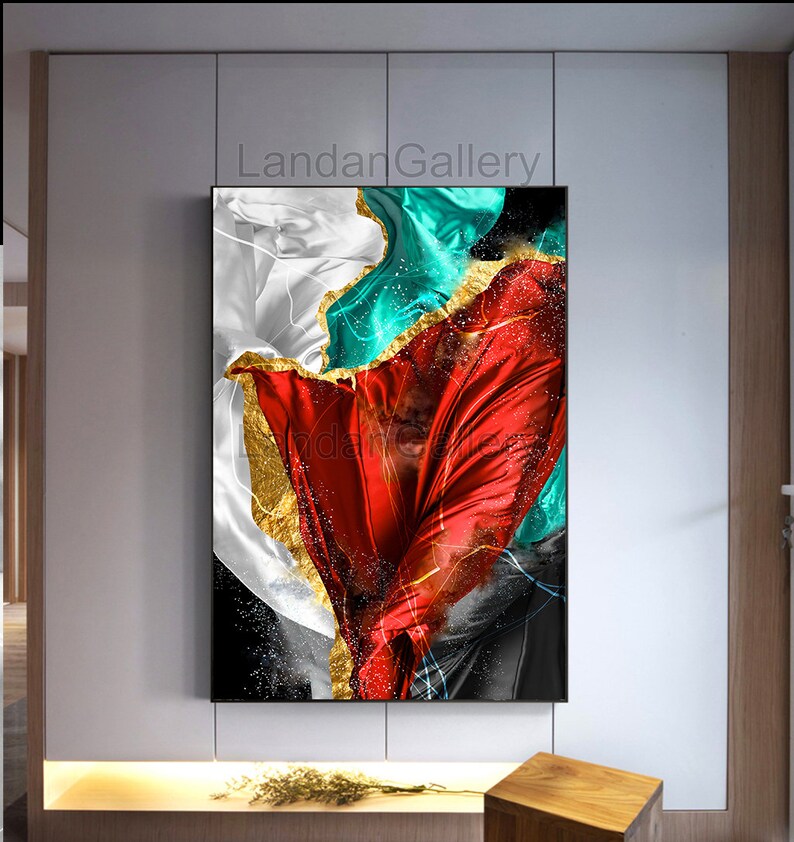 May include: Abstract art print featuring a red, white, and teal fabric with gold accents. The fabric is flowing and dynamic, creating a sense of movement. The background is black.