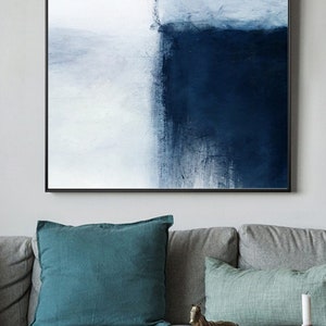 May include: Abstract painting with a black frame. The painting features a white background with a dark blue section on the right side. The dark blue section is painted with a textured brushstroke.