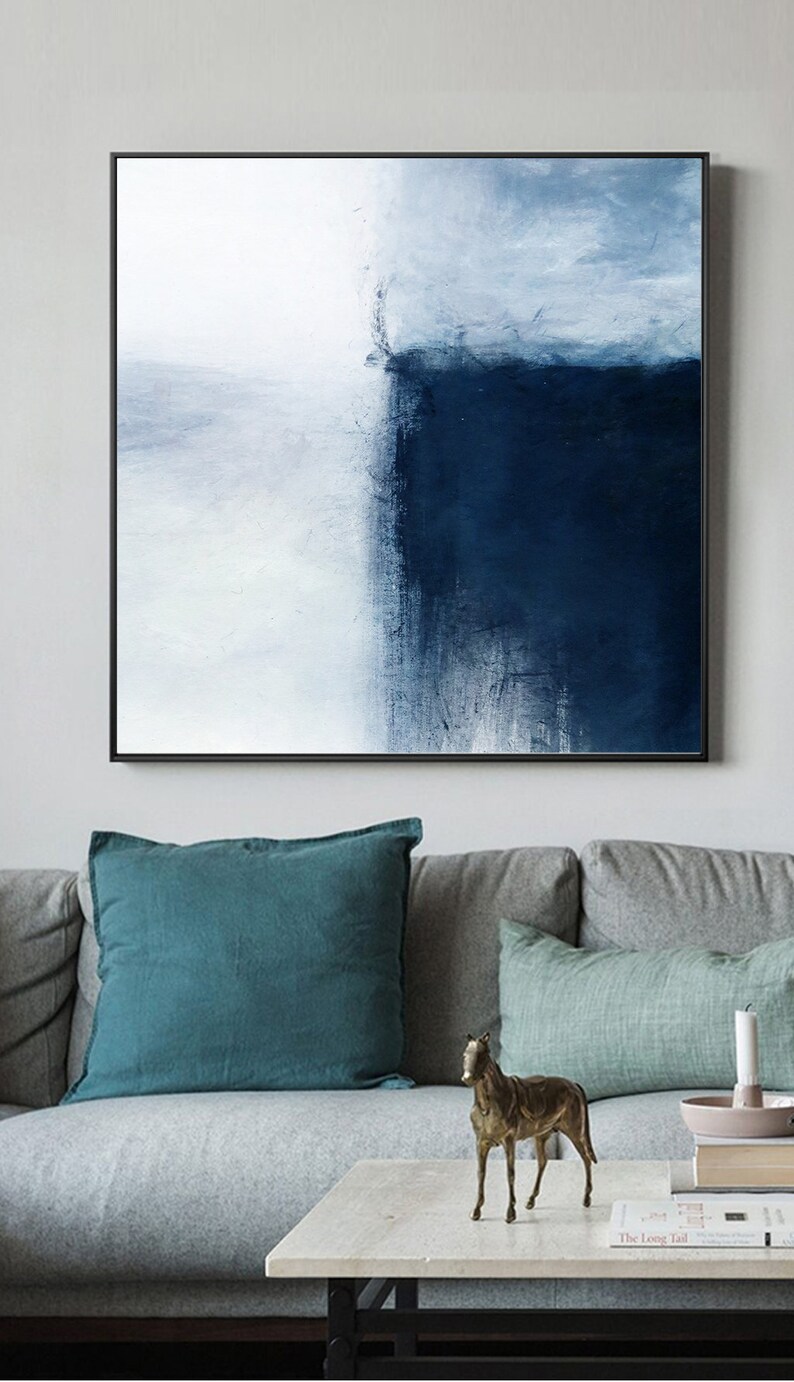 May include: Abstract painting with a black frame. The painting features a white background with a dark blue section on the right side. The dark blue section is painted with a textured brushstroke.