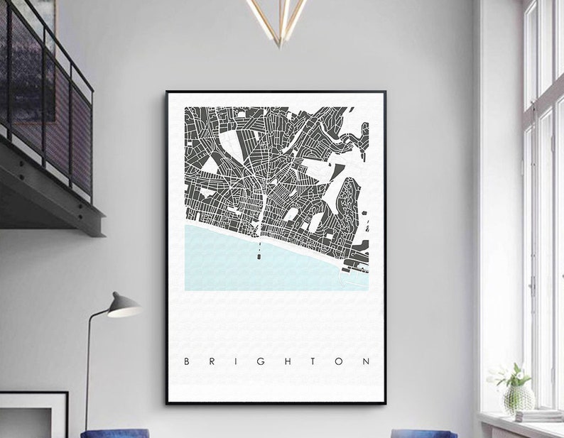 May include: A black and white map print of Brighton, England. The map shows the streets and coastline of the city. The word "Brighton" is printed in black at the bottom of the print.