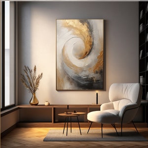 May include: Abstract painting with swirling gold and gray tones. The painting is framed and hanging on a wall in a living room setting with a white armchair and a small table.