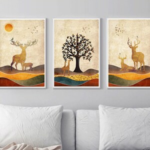 May include: Three framed prints with a nature theme. Each print features a deer, a tree, and a bird in a muted color palette of brown, gold, and green.