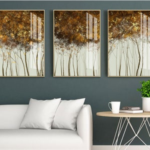Puede incluir: Tres impresiones art&iacute;sticas enmarcadas que representan una escena de bosque estilizada. La obra de arte tiene una paleta de colores dorados y marrones con una apariencia texturizada. Los &aacute;rboles se representan con troncos finos y oscuros sobre un fondo verde claro. Los marcos son dorados.