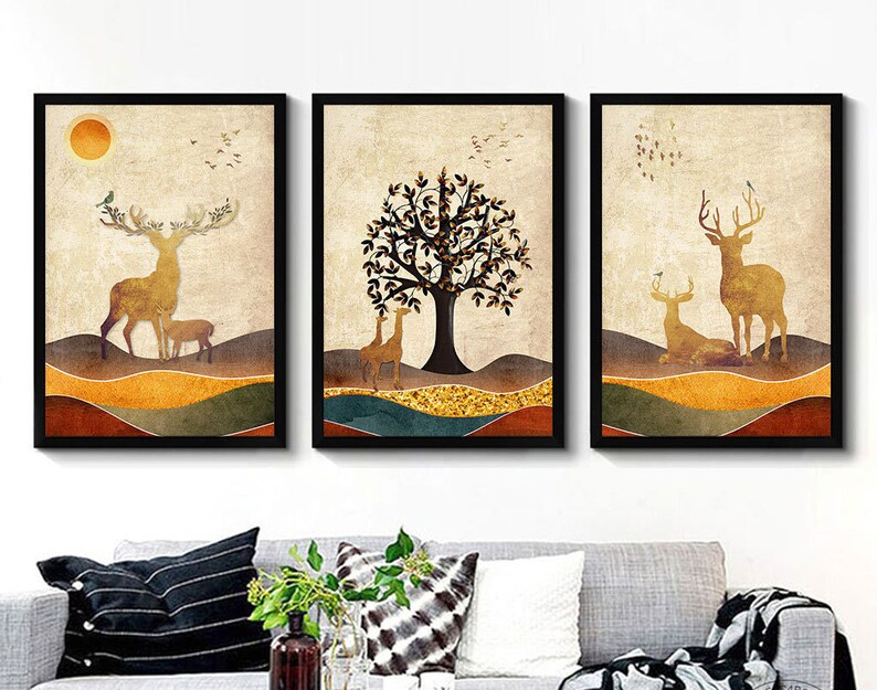 May include: A set of three framed prints featuring a stylized illustration of a forest scene with deer and a tree. The prints have a vintage aesthetic with a muted color palette of browns, yellows, and greens.