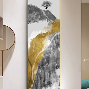 May include: Vertical framed art print featuring an abstract landscape. The artwork showcases a mountain scene with gray and gold watercolor-style textures. A bare tree and birds are silhouetted against a light gray sky. The frame is gold.