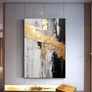 Puede incluir: Pintura abstracta con pintura dorada, negra y blanca sobre un lienzo. La pintura tiene un estilo moderno y contemporáneo.