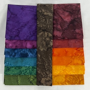 May include: A set of 10 fabric squares in various shades of purple, red, blue, green, and orange. The fabric has a tie-dye pattern with a brown background.