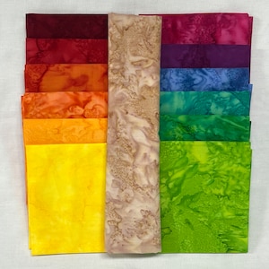 May include: A collection of 18 fabric squares in various shades of red, orange, yellow, green, blue, and purple. The fabric has a tie-dye pattern.