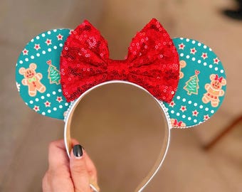 May include: Red sequin bow headband with teal blue fabric mouse ears featuring a gingerbread man and Christmas tree pattern.