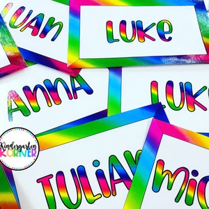 Puede incluir: Un conjunto de etiquetas de nombre de arcoíris coloridas con los nombres Anna, Juan, Luke, Tulia y Mich escritos en negro. Las etiquetas de nombre tienen un borde de arcoíris y son perfectas para un aula o una fiesta.