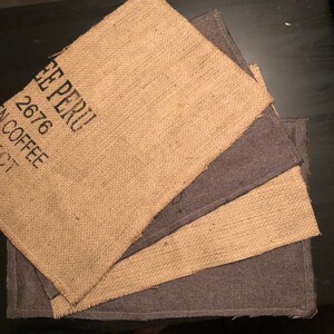 May include: Four placemats made from burlap fabric. The top placemat has the text "Cafe Peru 2676 Coffee" printed on it.