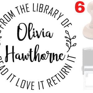 May include: Black and white self-inking stamp with the text "From the Library of Olivia Hawthorne Read it Love it Return it" and a floral design. The stamp is mounted on a wooden handle.