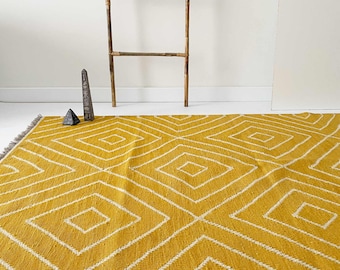 May include: A mustard yellow rug with a white diamond pattern. The rug has a fringe border.