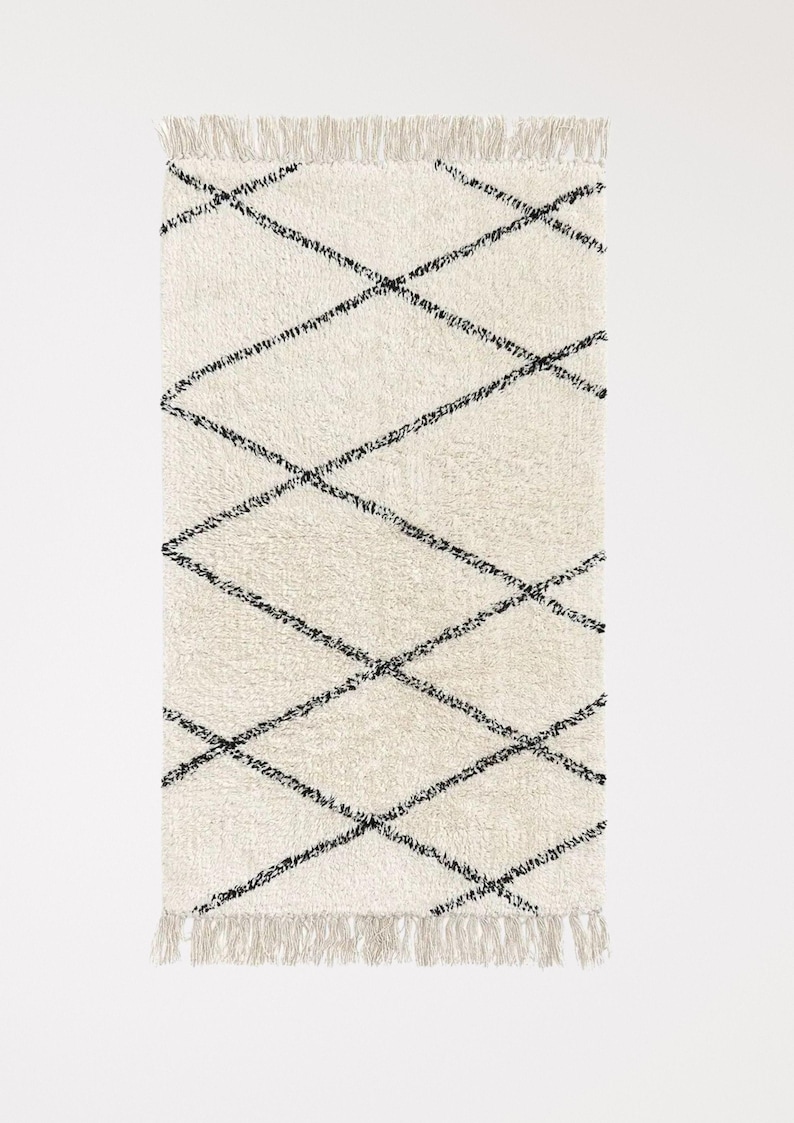 May include: A white and black diamond patterned rug with fringe on all sides.