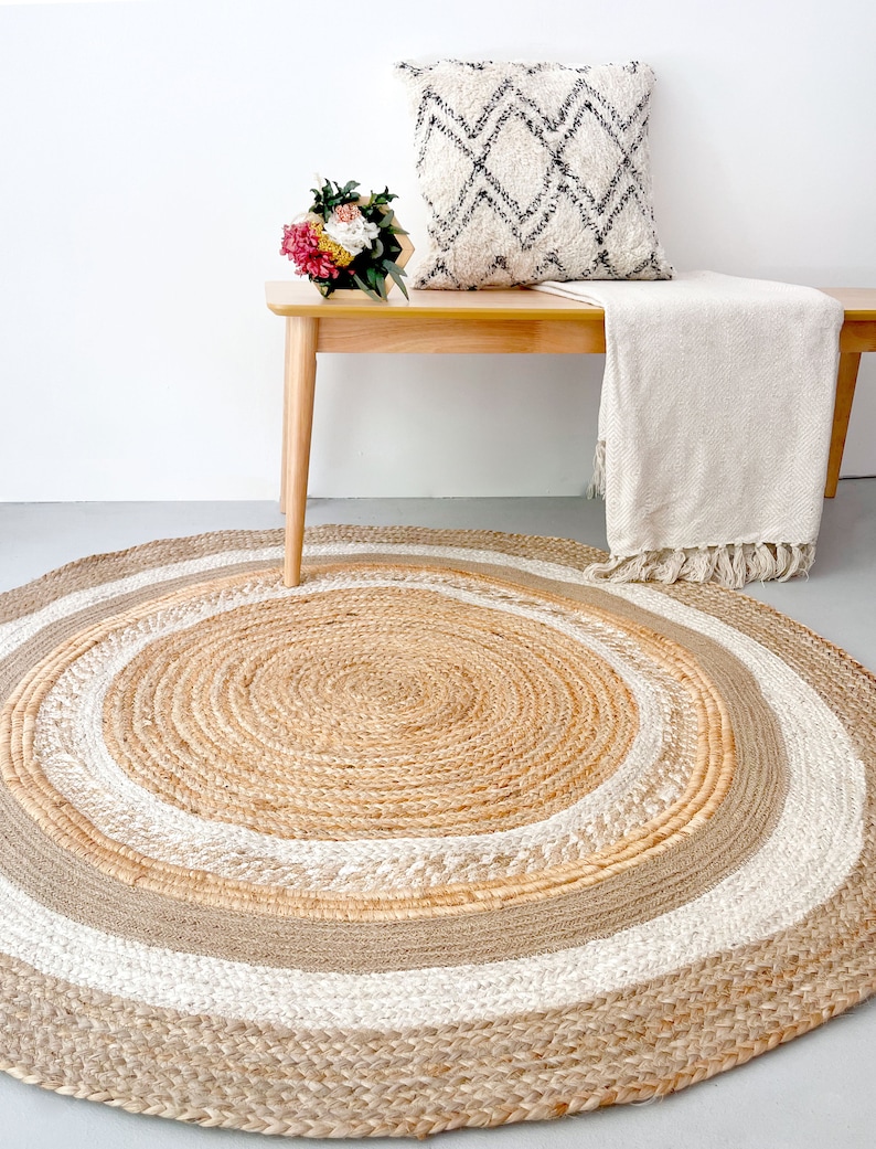 May include: A round jute rug with a white and beige striped border. The rug is made of natural fibers and has a rustic, bohemian style.