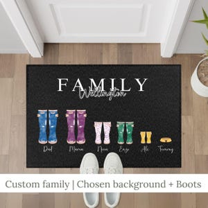 May include: Black doormat with the word "FAMILY" and "Wellington" in white. Features illustrations of colorful rain boots labeled "Dad," "Mama," "Nina," "Enzo," and "Ale." A dog bowl is labeled "Tommy." Text at the bottom reads "Custom family | Chosen background + Boots."