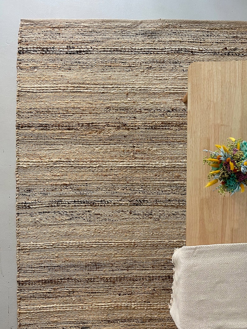 A stylish hallway decorated with a long, durable jute rug runner in natural and cream tones plus black