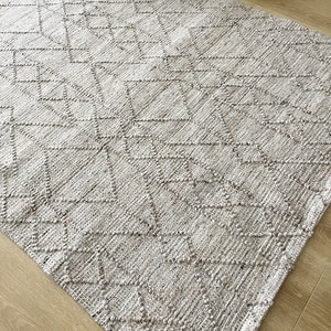 May include: A light gray woven rug with a diamond pattern. The rug has a textured surface and is made of natural fibers.