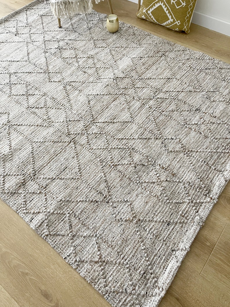 May include: A light gray woven rug with a diamond pattern. The rug has a textured surface and is made of natural fibers.