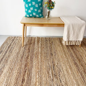 A cozy living room featuring a large, striped jute rug, enhancing the space with warmth and elegance