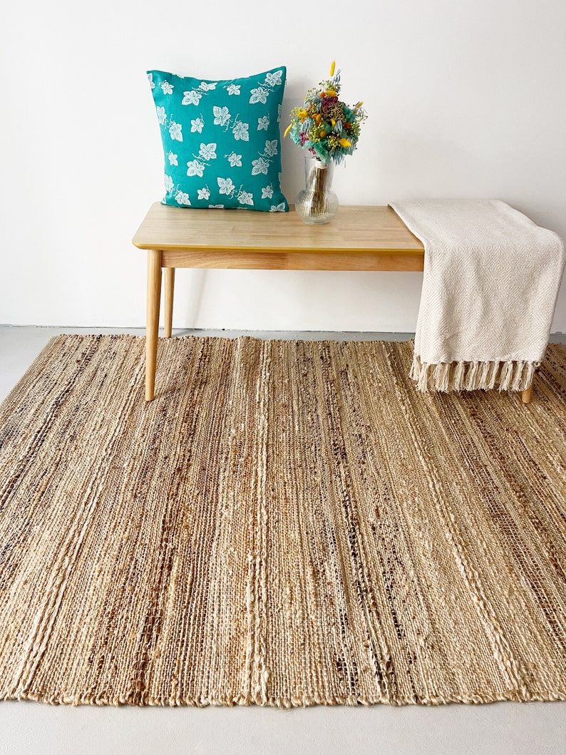A cozy living room featuring a large, striped jute rug, enhancing the space with warmth and elegance