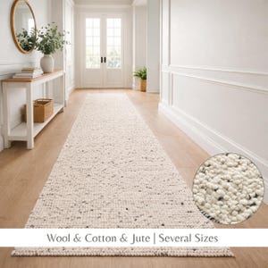 May include: An off-white runner rug with a speckled design, made from wool, cotton, and jute. The rug is shown in a hallway with light wood flooring and white walls. The rug is available in several sizes. The rug's texture is visible in a close-up.