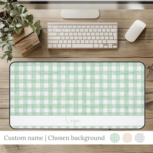 May include: A rectangular desk mat with a light green and white gingham pattern. The mat has a white rectangular section with the name "Vega" in cursive. The text "Custom name | Chosen background" is at the bottom.