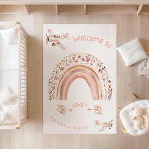 Puede incluir: Alfombra rectangular con un diseño de acuarela que presenta un arcoíris, aviones y elementos florales. El texto "Welcome to Sara's Rainbow Room" se muestra en un tono rosa suave. La alfombra está diseñada para una habitación infantil.