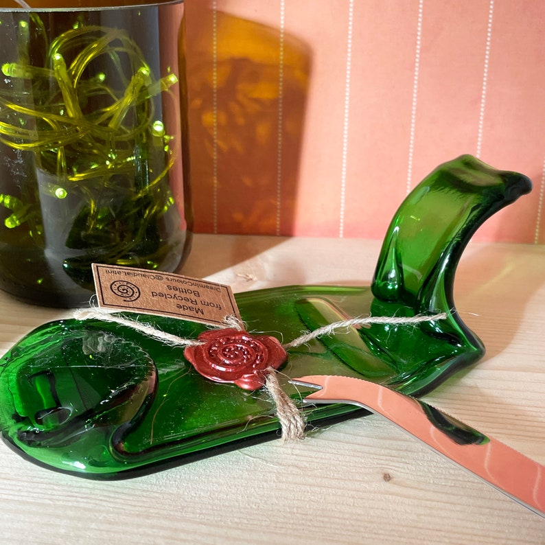 May include: A green glass serving dish made from recycled bottles with a small knife and a wax seal that says "Made from Recycled Bottles GreenWood Creations".
