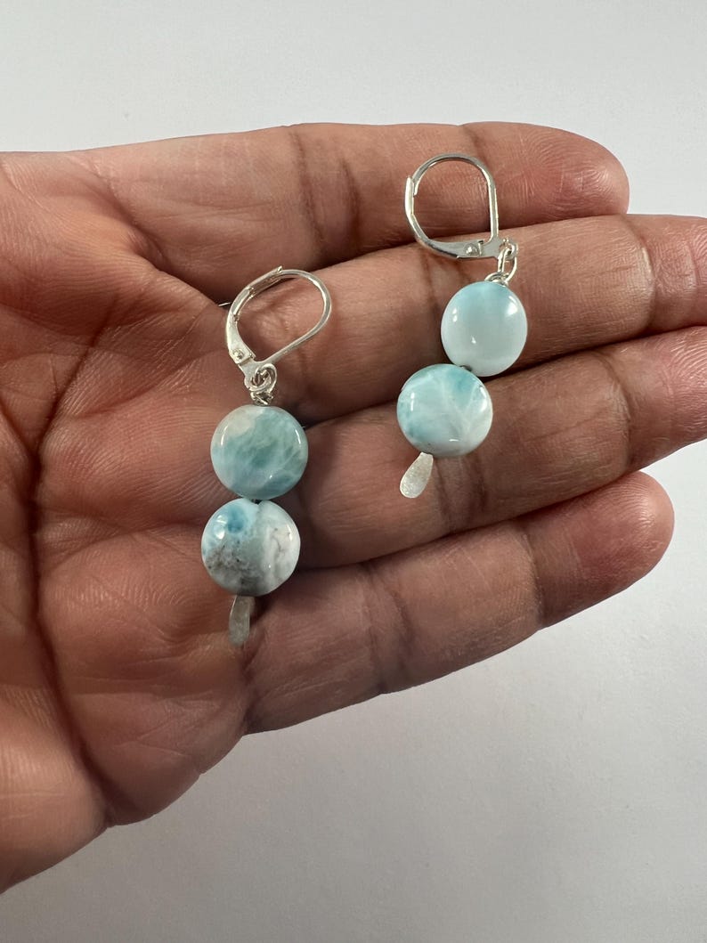 May include: A pair of silver dangle earrings with two round blue and white gemstone beads on each earring.