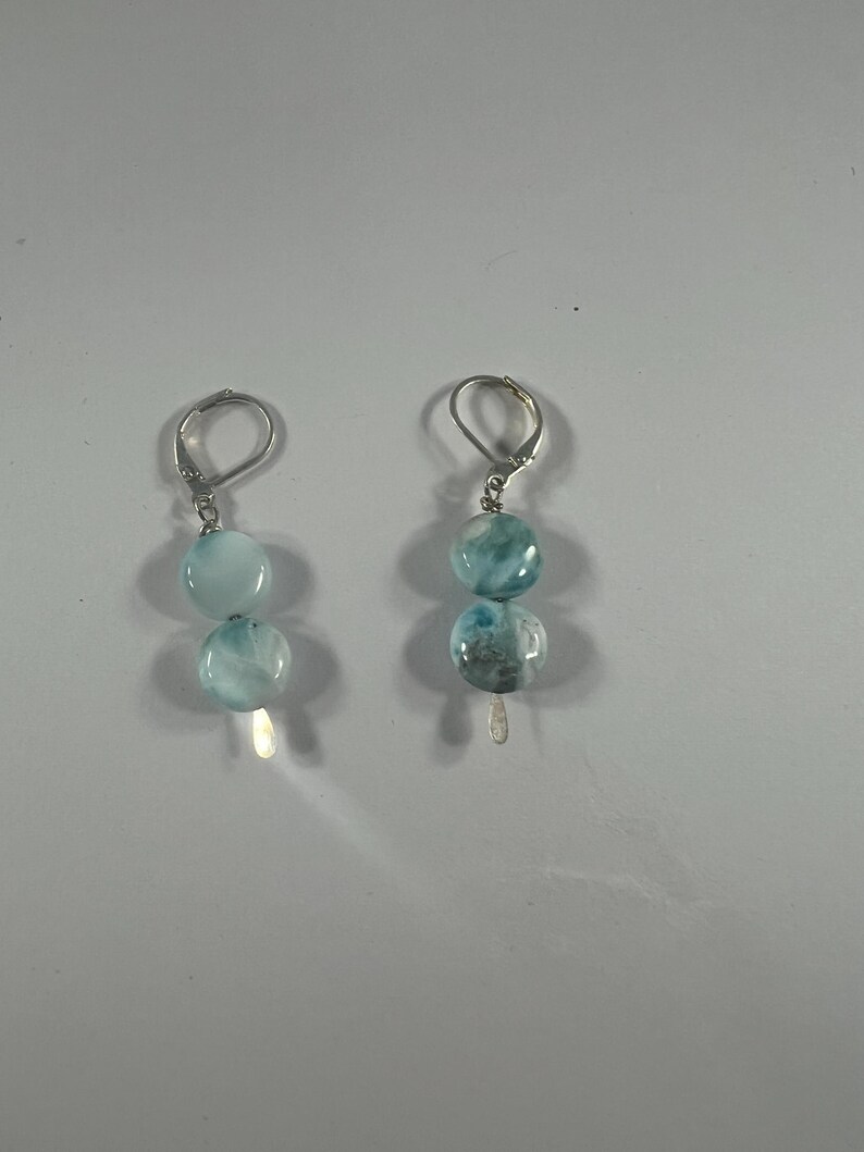 May include: A pair of silver earrings with blue and white gemstone beads.