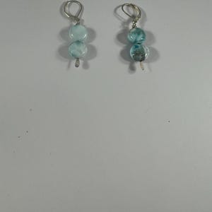 May include: A pair of silver earrings with two blue and white gemstone beads on each earring.