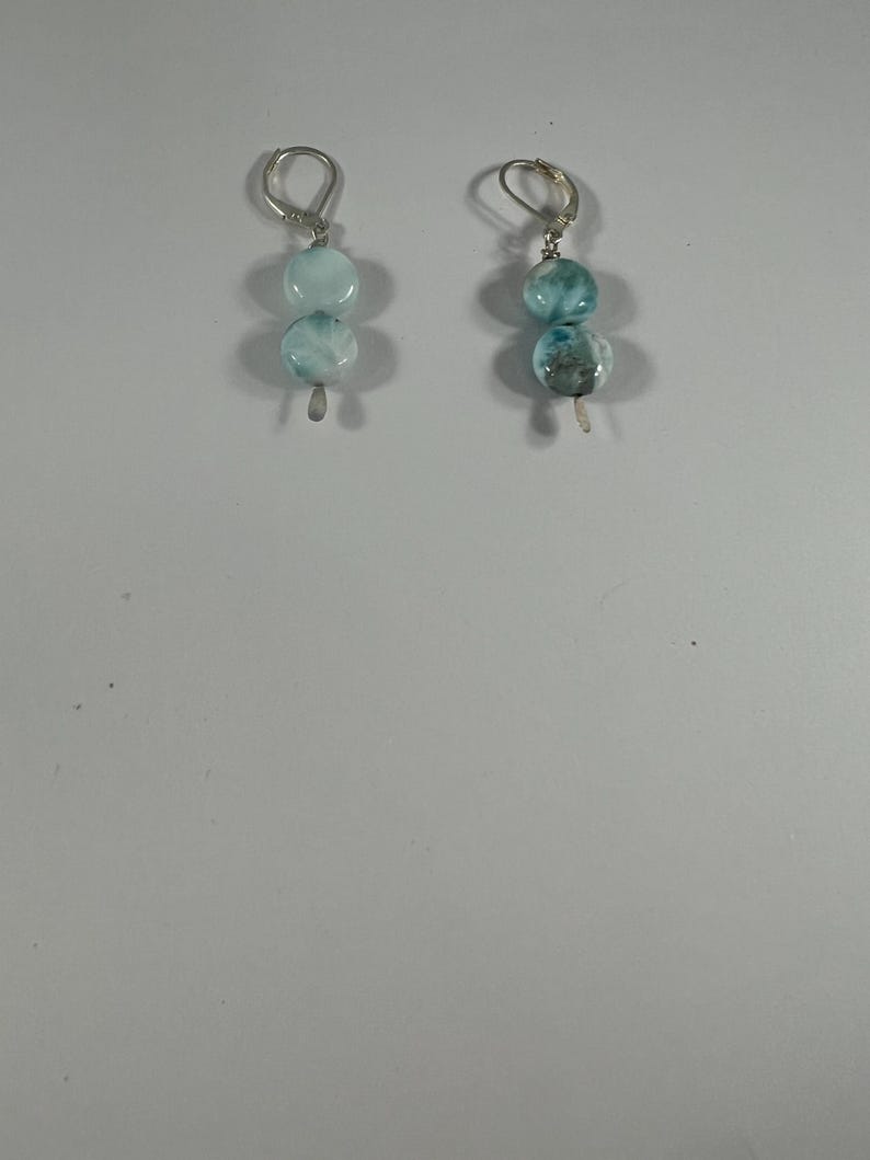 May include: A pair of silver earrings with two blue and white gemstone beads on each earring.