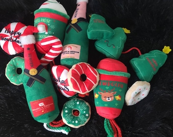 May include: A collection of plush Christmas-themed toys, including a red and white candy cane, a green and red Santa Claus mug, a green and white champagne bottle, a green and white donut, a green and white Christmas tree, and a red and white Christmas mug.