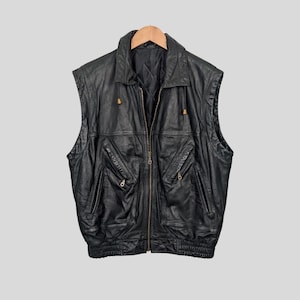 May include: Black leather vest with a zipper closure and multiple pockets. The vest has a stand-up collar and a drawstring at the neck.