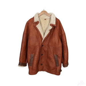 Könnte beinhalten: Eine braune Lederjacke mit Lammfellfutter.