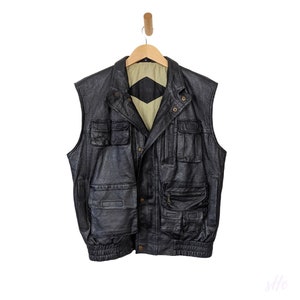 May include: A black leather vest with multiple pockets and a zipper closure. The vest has a brown lining and a diamond-shaped patch on the back.