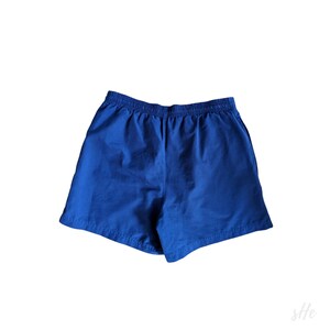 以下が含まれることがあります： ゴムウエストの青いスポーツショーツです。