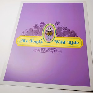 May include: A rectangular poster with a purple background featuring the text Mr. Toad's Wild Ride in blue letters on a yellow banner. Above the banner is a central illustration of a toad character surrounded by various animal figures.