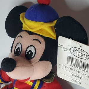 Puede incluir: Un peluche de Mickey Mouse vestido de cascanueces, con una chaqueta roja con ribetes amarillos, un sombrero azul y amarillo con un pomp&oacute;n rojo y una etiqueta blanca que dice MADE EXCLUSIVELY FOR THE DISNEY STORE NUTCRACKER MICKEY BE.