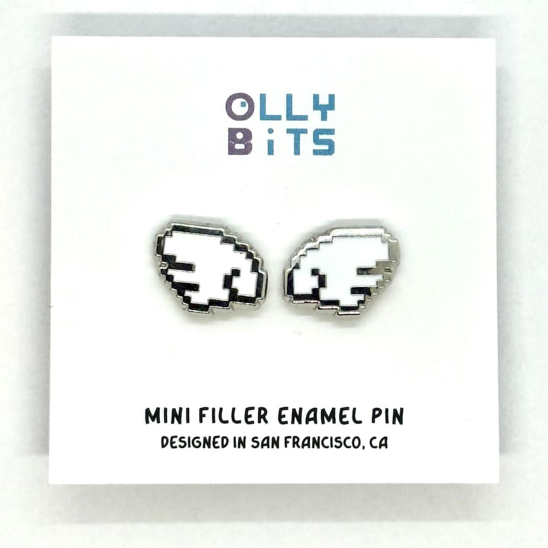 Puede incluir: Un par de pines de esmalte blanco pixelado con forma de ala y bordes plateados. Los pines se muestran en una tarjeta blanca con el texto "Olly Bits" en morado y azul, y "Mini Filler Enamel Pin" y "Designed in San Francisco, CA" en negro.