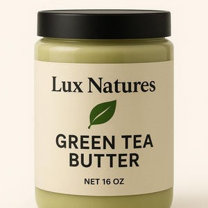 May include: A jar of green tea butter with a black lid. The label reads "Lux Natures" above a green leaf graphic, followed by "GREEN TEA BUTTER" and "NET 16 OZ". The jar has a light green color.