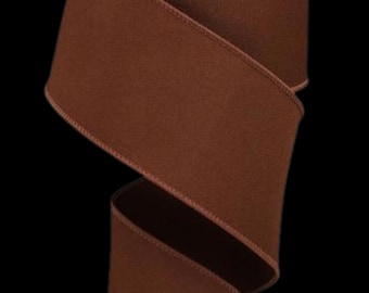 May include: A solid dark brown ribbon with a smooth, matte texture and finished edges. The ribbon is folded into a loose, flowing S-curve shape, showcasing its consistent color and uniform fabric weave against a plain black background.