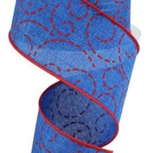 May include: A spool of blue ribbon with a red stitched swirl pattern. The ribbon has a red border and is made of a textured fabric. The spool is white and the ribbon is spiraling downwards.